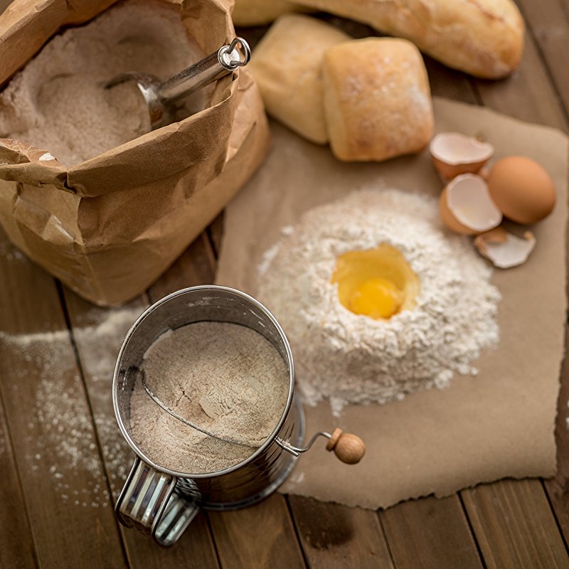 A wooden table topped with flour sifter for making bread