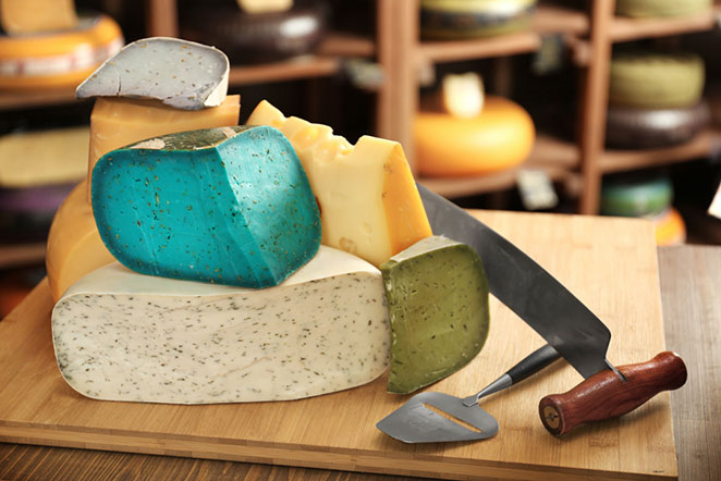 A variety of cheeses on a cutting board with a knife