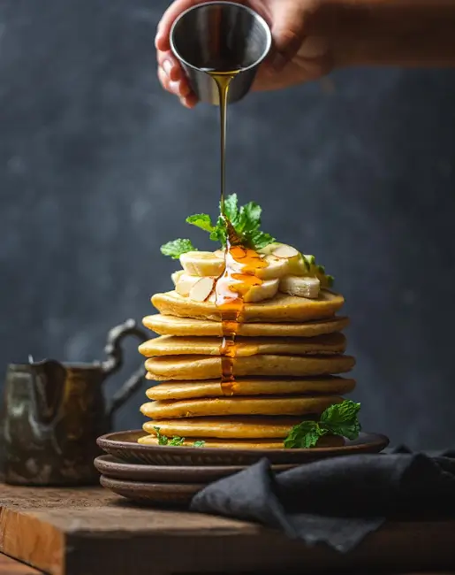 A stack of pancakes being drizzled with syrup